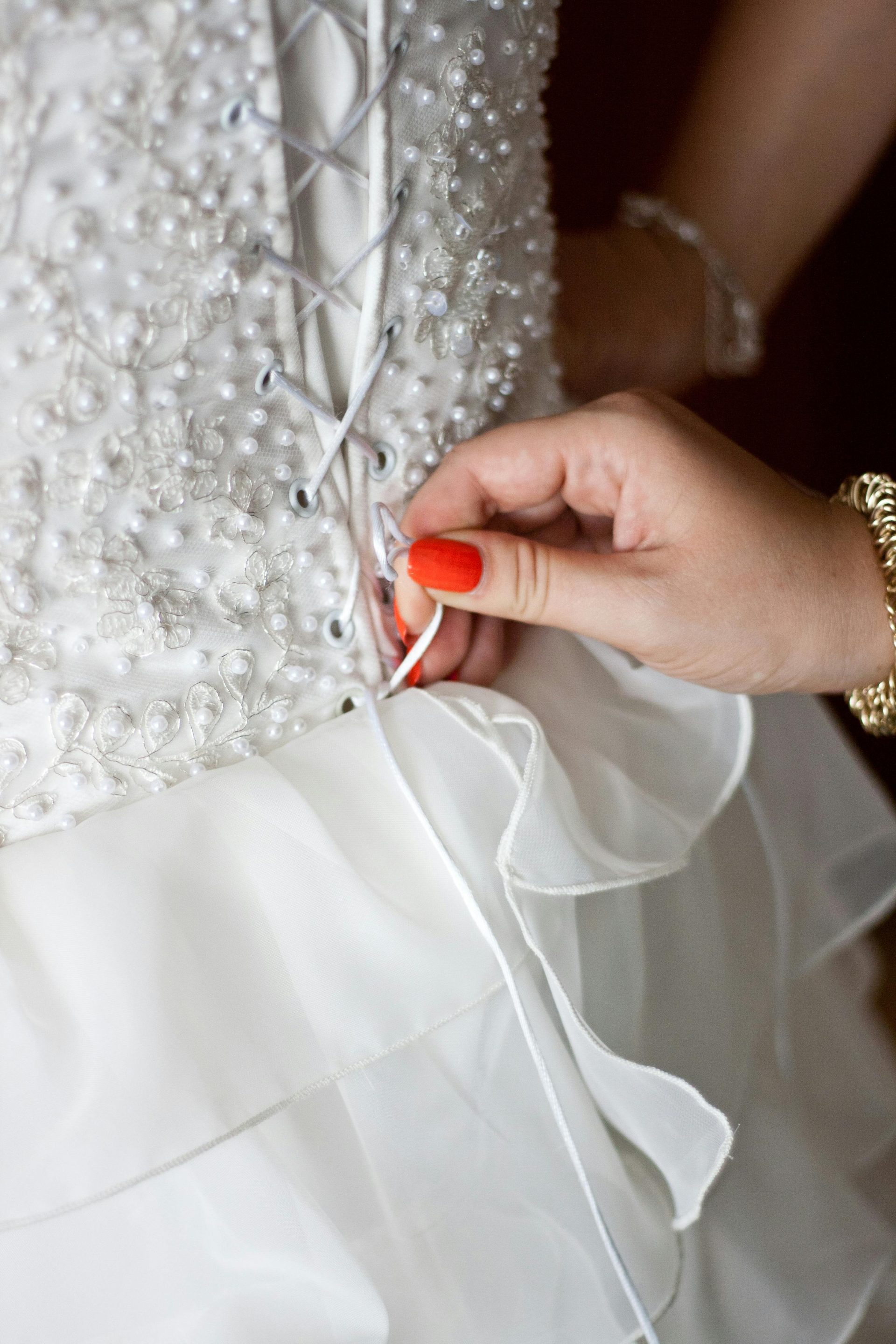 A detailed close-up of a bride's lace-up wedding dress with intricate beadwork.
